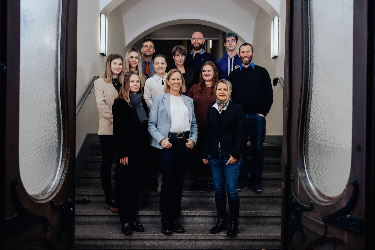 Die zwölf Mitarbeiterinnen und Mitarbeiter auf einer Treppe